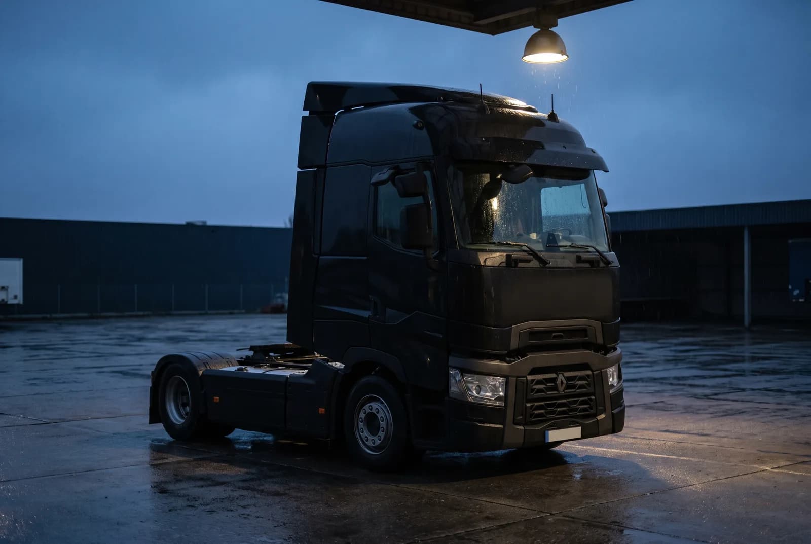 A single tractor unit without a trailer, parked in a depot at blue hour